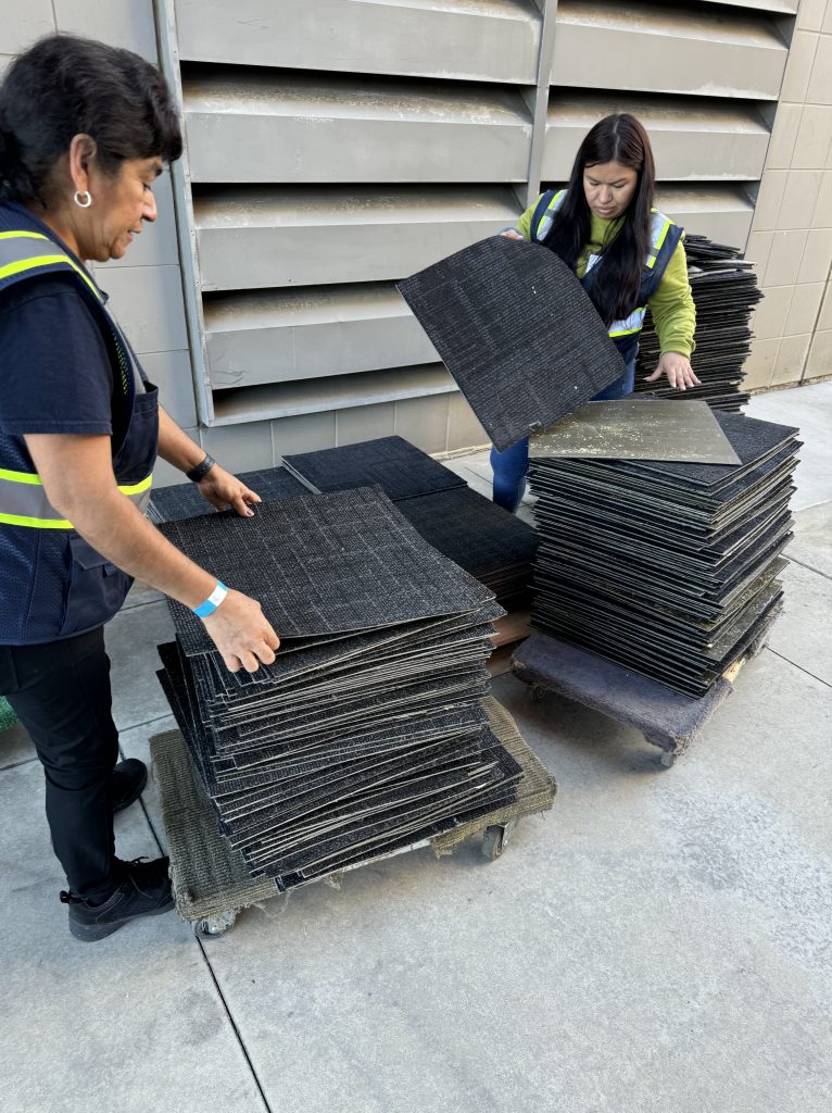 Workers remove carpet tile destined for reuse.